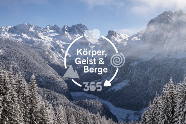 Schneebedeckte Berge und Wald mit einer kreisförmigen grafischen Überlagerung, die in der Mitte „Body, Mind & Mountains 365” anzeigt.