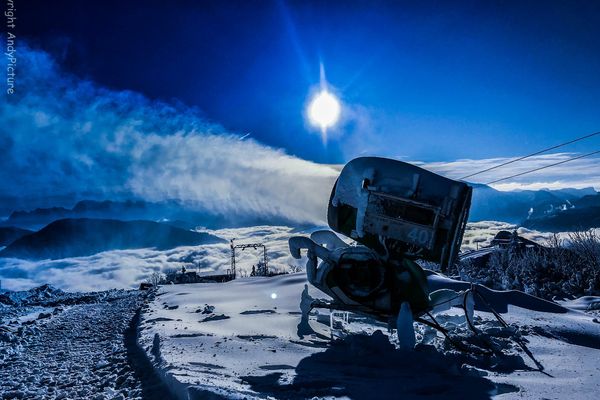 Schneekanone im Schnee, Nebelmeer im Tal bei Nacht und Vollmond
