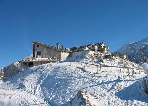 Die Simonyhütte thront auf schneebedecktem Fels, umgeben von Sonne, Eis und majestätischen Gipfeln.
