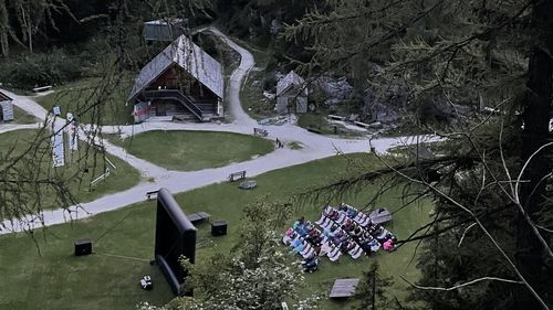 Freiluftkino bei einer Almhütte in einer Berglandschaft unter rosa Abendhimmel, umrahmt von Bäumen.