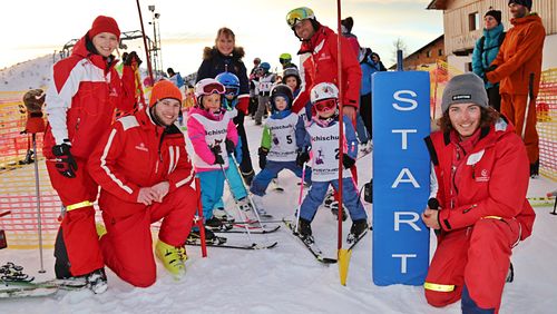 Lächeln am Start – Rennkids mit Skilehrer:innen bereit für den großen Moment.