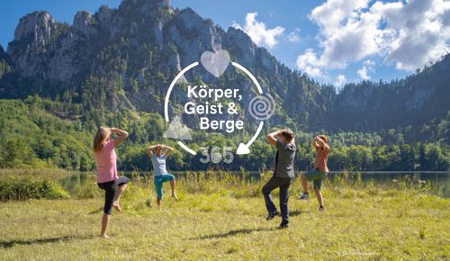 Vier Menschen, die an einem Bergsee im Freien Sport treiben. Auf dem Bild steht „Body, Mind & Mountains 365“.