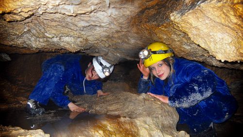 Two children explore Koppenbrüller cave with helmets and headlamps in Obertraun at Dachstein, Salzkammergut.