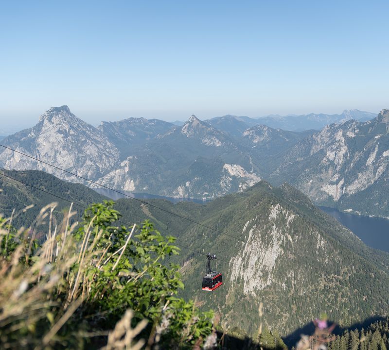 The Feuerkogel mountain railway glides over green mountain slopes, offering views of Lake Traunsee and rugged peaks, all the way up to the Feuerkogel.
