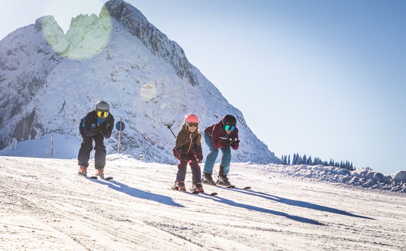 Familie auf Ski fährt die Piste in Dachstein West hinunter