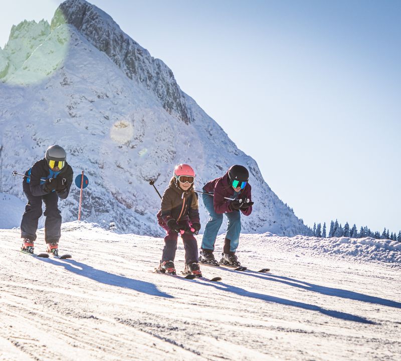 Familie auf Ski fährt die Piste in Dachstein West hinunter