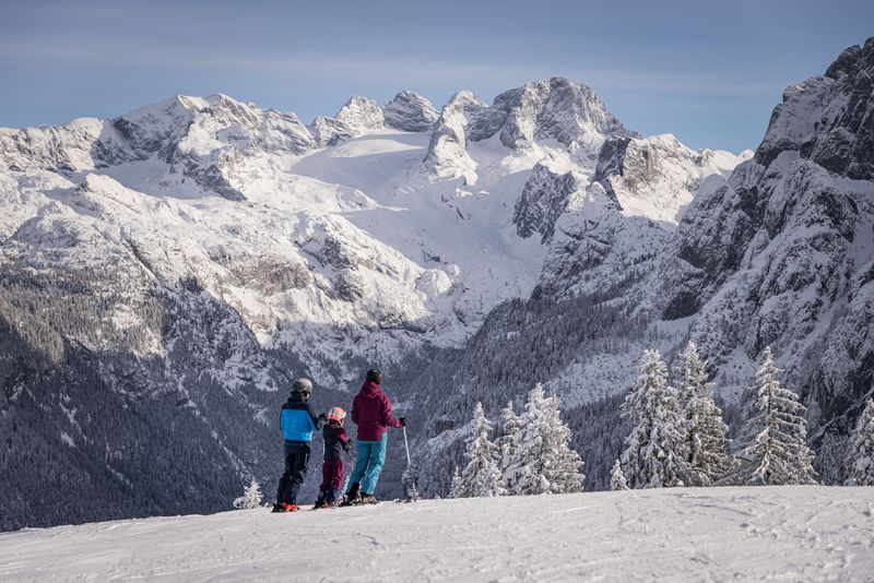 Familie steht auf der Piste in Dachstein West und blickt auf den Gletscher