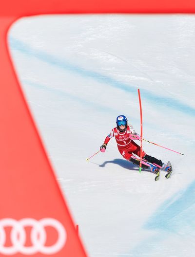 Skirennläuferin in rotem Anzug bei einem Slalom auf verschneiter Piste, teilweise von einer roten Audi-Werbebande eingerahmt.