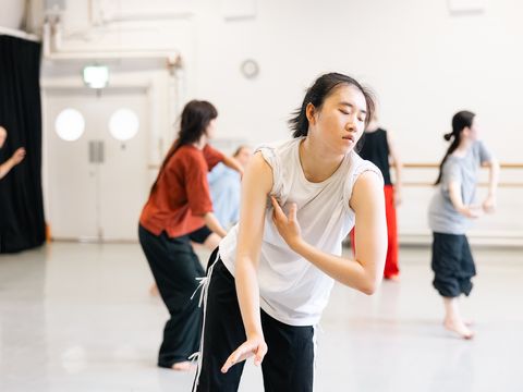 A group of dancers in a studio perform an expressive routine, each in unique poses, focusing on fluid movements and expression.