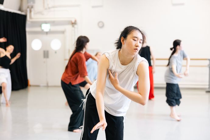 A group of dancers in a studio perform an expressive routine, each in unique poses, focusing on fluid movements and expression.