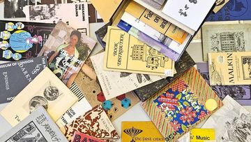 A collection of colorful zines and booklets scattered on a surface, featuring various illustrations, text, and cover designs.