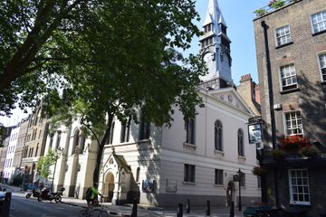 White building on leafy London street with a tree across the road, basking it in shade