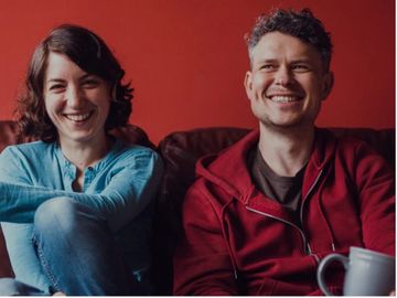 man and woman laughing against red background
