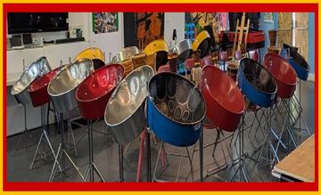 A room filled with colorful steel drums on stands, surrounded by musical equipment and bright wall art.