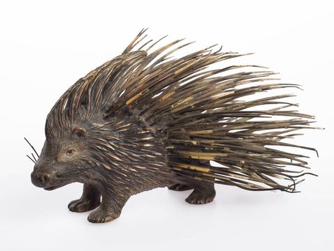 A detailed wooden porcupine sculpture with long, sharp quills.
