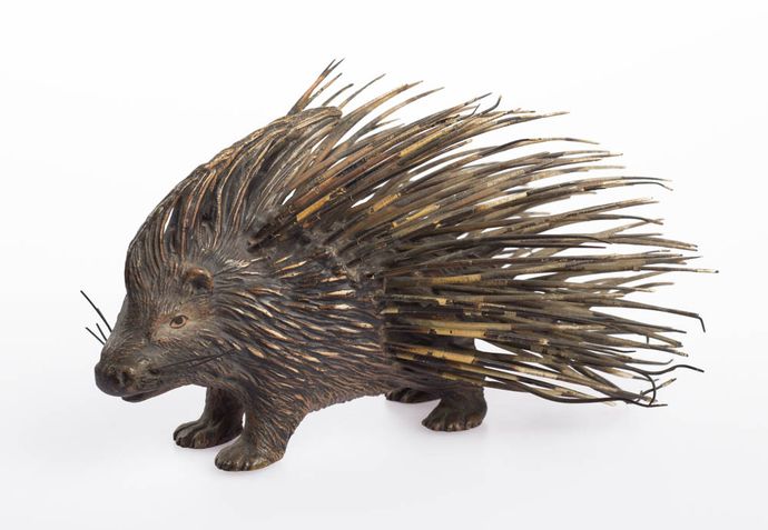 A detailed wooden porcupine sculpture with long, sharp quills.