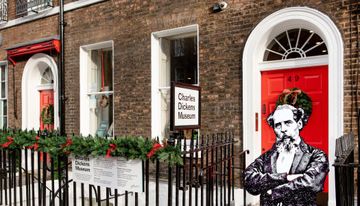 Historic brick building housing the Charles Dickens Museum, featuring bright red doors and festive decorations.