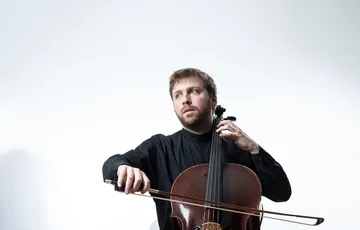 Individual plays with musical instrument in a well lit room looking away from camera