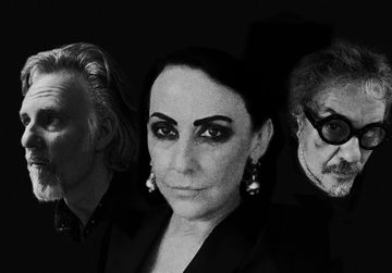 Three people with somber expressions in a black-and-white portrait against a dark background, featuring dramatic lighting.