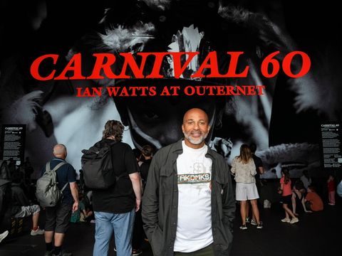 Man standing in front of a large "Carnival 60" display, surrounded by a crowd.