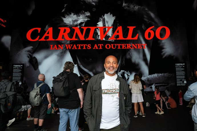 Man standing in front of a large "Carnival 60" display, surrounded by a crowd.