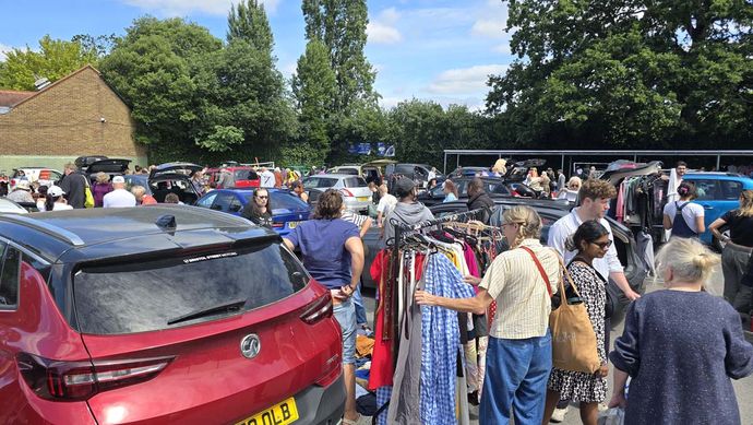 A car park with a crowd of people selling clothes