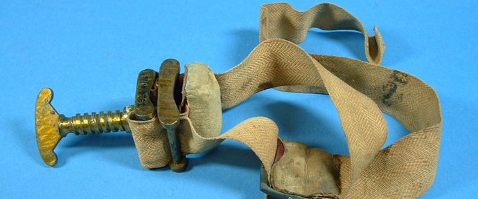 Vintage tourniquet with a brass screw clamp and beige fabric strap, set against a blue background.