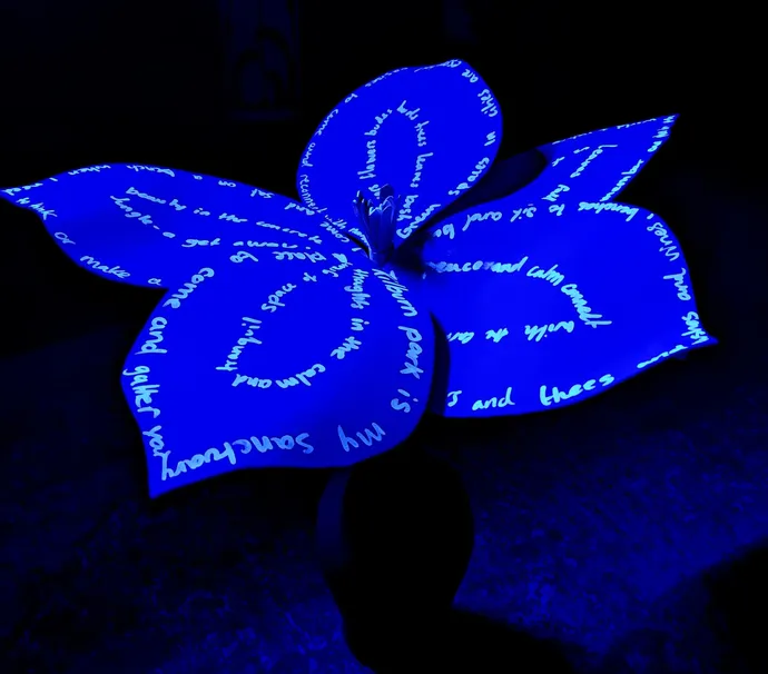 A luminous blue plant with large leaves displaying handwritten words in white, set against a dark background.