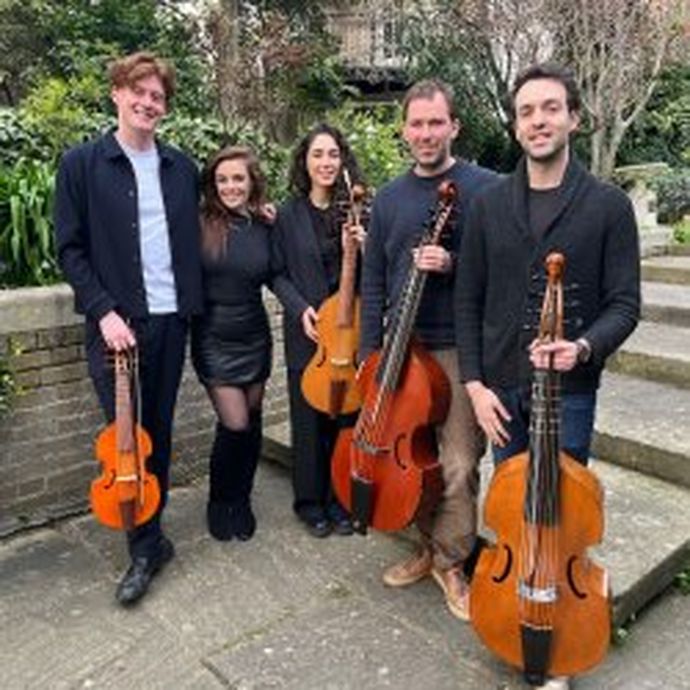 Five people standing outdoors, holding string instruments. Three men and two women, smiling, with greenery and steps in the background.