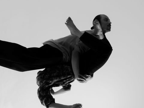 Black and white photo of two people embraced in contorted movement, limbs are difficult to distringuish while suspending in air