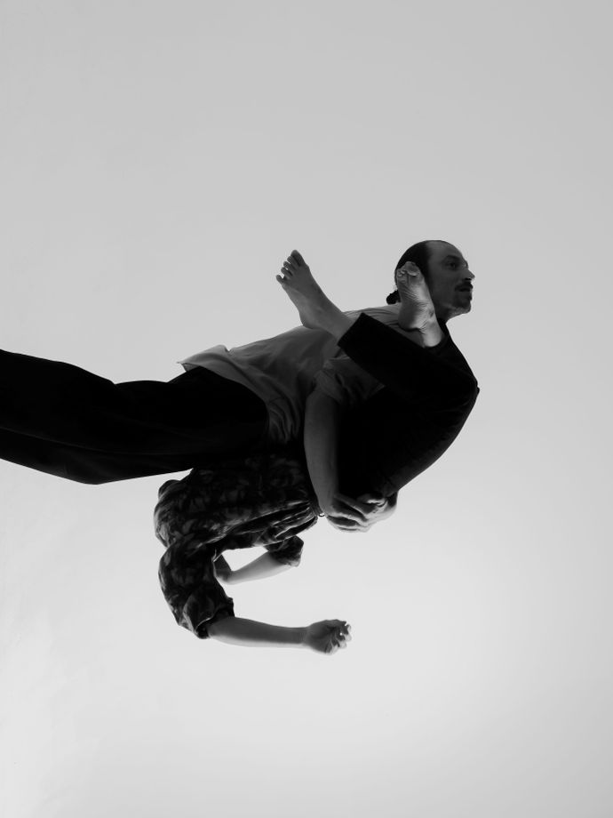 Black and white photo of two people embraced in contorted movement, limbs are difficult to distringuish while suspending in air