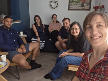 Six people gathered in a living room, posing for a casual group photograph indoors.