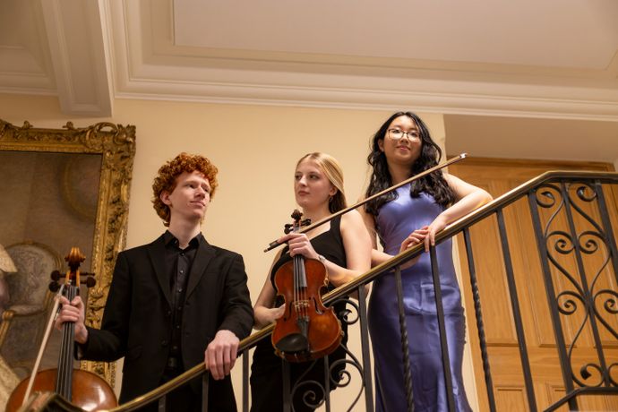 3 individuals on staircase holding instruments
