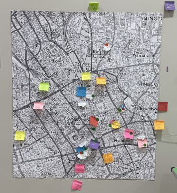 A detailed city map on a wall, featuring various colorful pins and sticky notes marking locations, with areas like King’s Cross and Holborn visible.