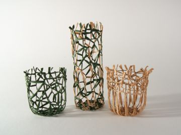 Three woven baskets of varying heights, two green and one natural, displayed on a light background.