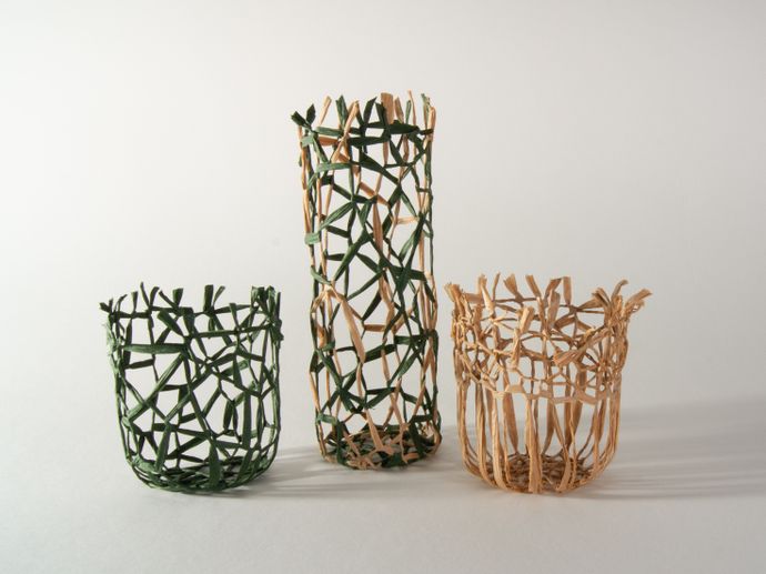 Three woven baskets of varying heights, two green and one natural, displayed on a light background.