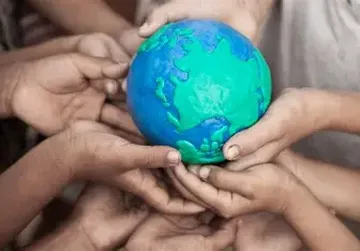 Children's hands holding a small, colorful model of Earth, symbolizing unity and global care.