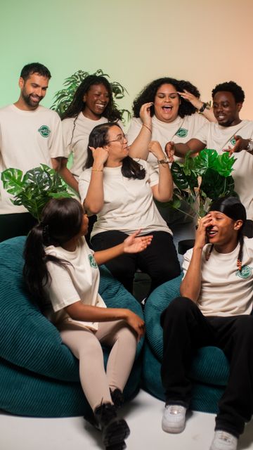 6 young people joking and laughing with one another in branded t shirts