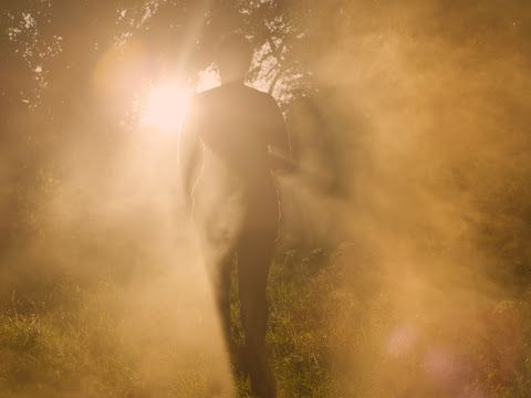 A dark figure walking in the forest covered by smoke