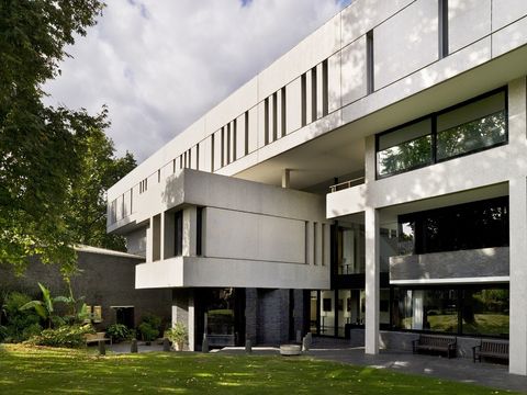 Modern beige building with green lawn at front and blue cloudy sky above