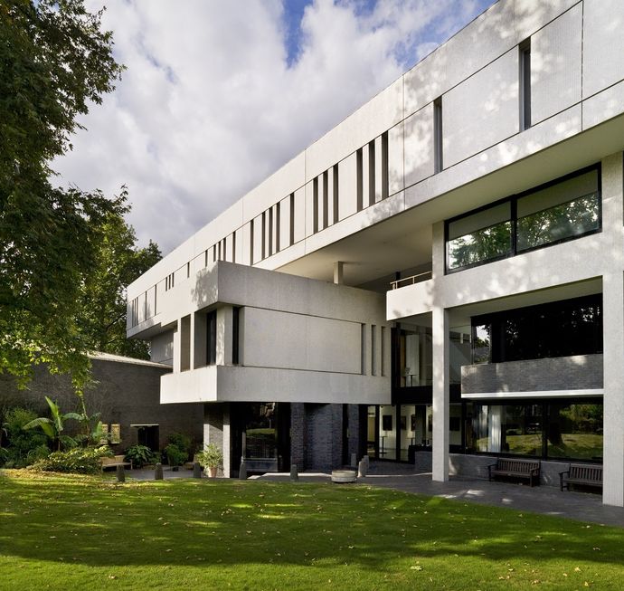 Modern beige building with green lawn at front and blue cloudy sky above