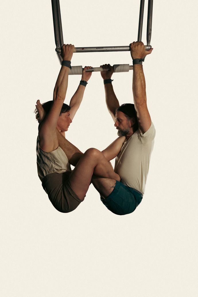 2 indidviduals interlocking their logs hanging from an apparatus.