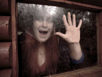 Individual screaming out on window with hands