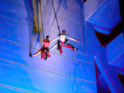 Two people scaling large structure with blue lights shining on it
