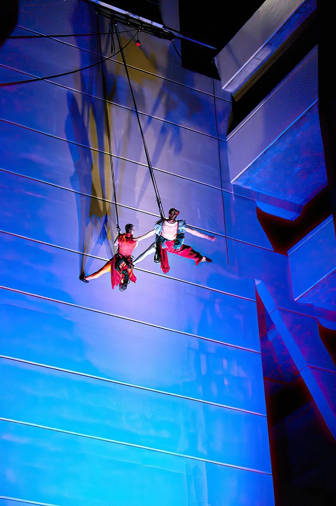Two people scaling large structure with blue lights shining on it