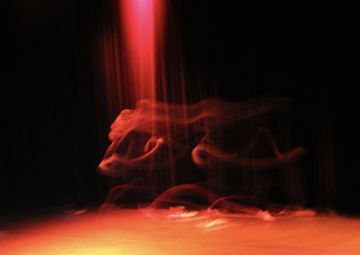 Abstract image of motion blur with red and orange light streaks against a dark background, creating a dynamic and mysterious atmosphere.