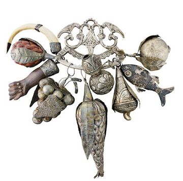 Ornate antique charm cluster featuring miniature fish, hand, horn, fruit, and decorative metal pendants.