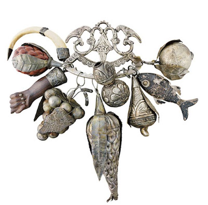 Ornate antique charm cluster featuring miniature fish, hand, horn, fruit, and decorative metal pendants.