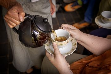 Tea from teapot being poured into teacup