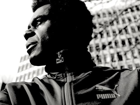 Black and white photo of person looking to distance wearing puma jacket and towerblock in background